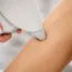 Głowica lasera przyłożona do skóry na nodze podczas depilacji laserowej w gabinecie