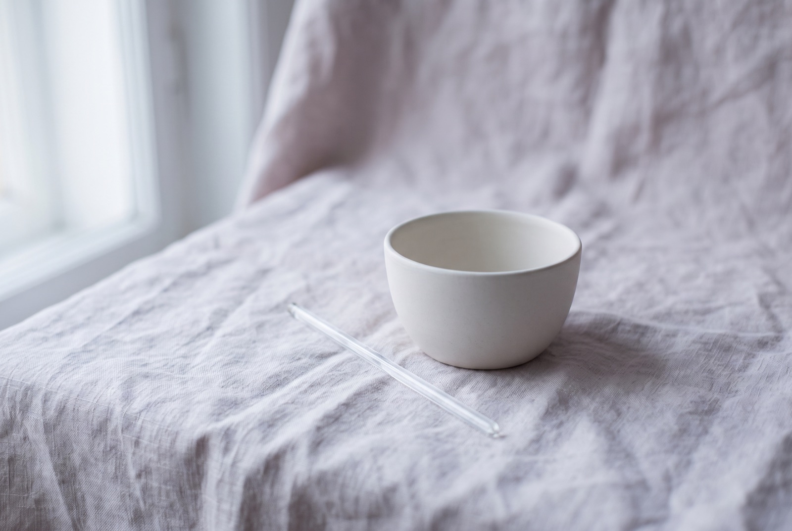 martwa natura - ceramiczna miseczka i szklana bagietka na lnianej tkaninie